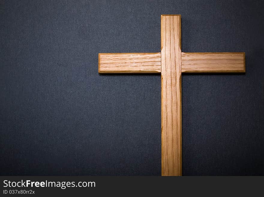 Wooden cross against dark grey background with copyspace