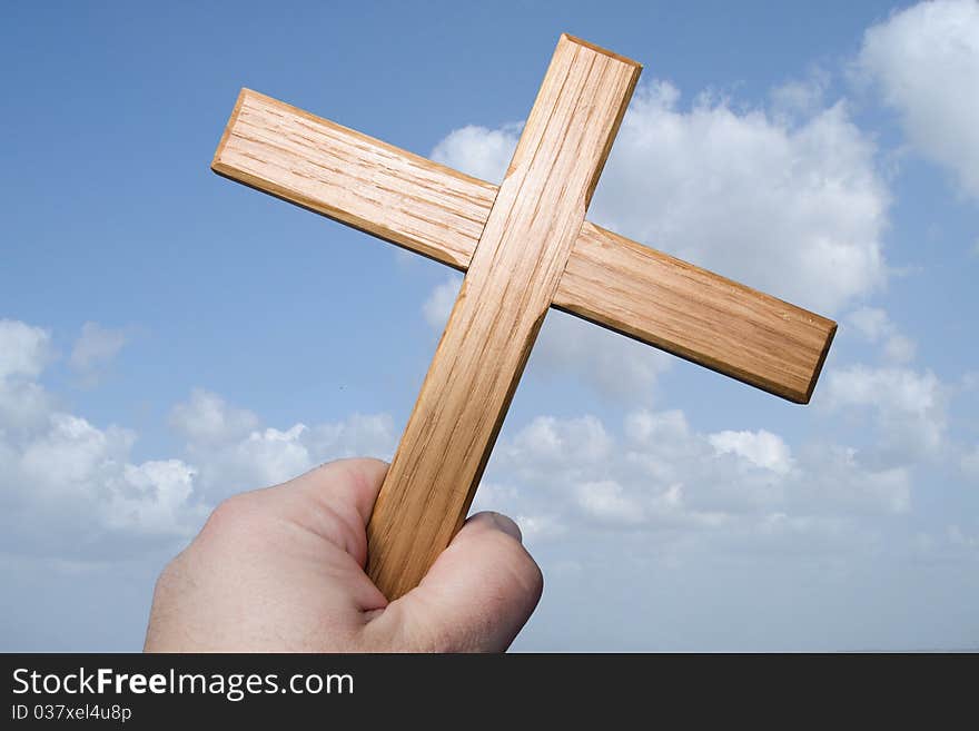 Wooden cross against blue sky with clouds