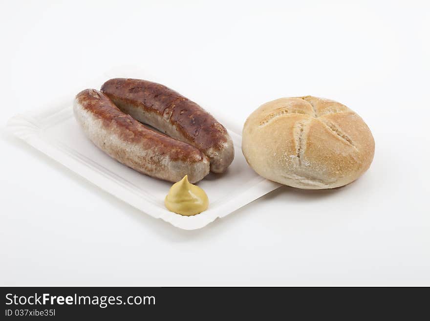 A pair of fried sausages with mustard