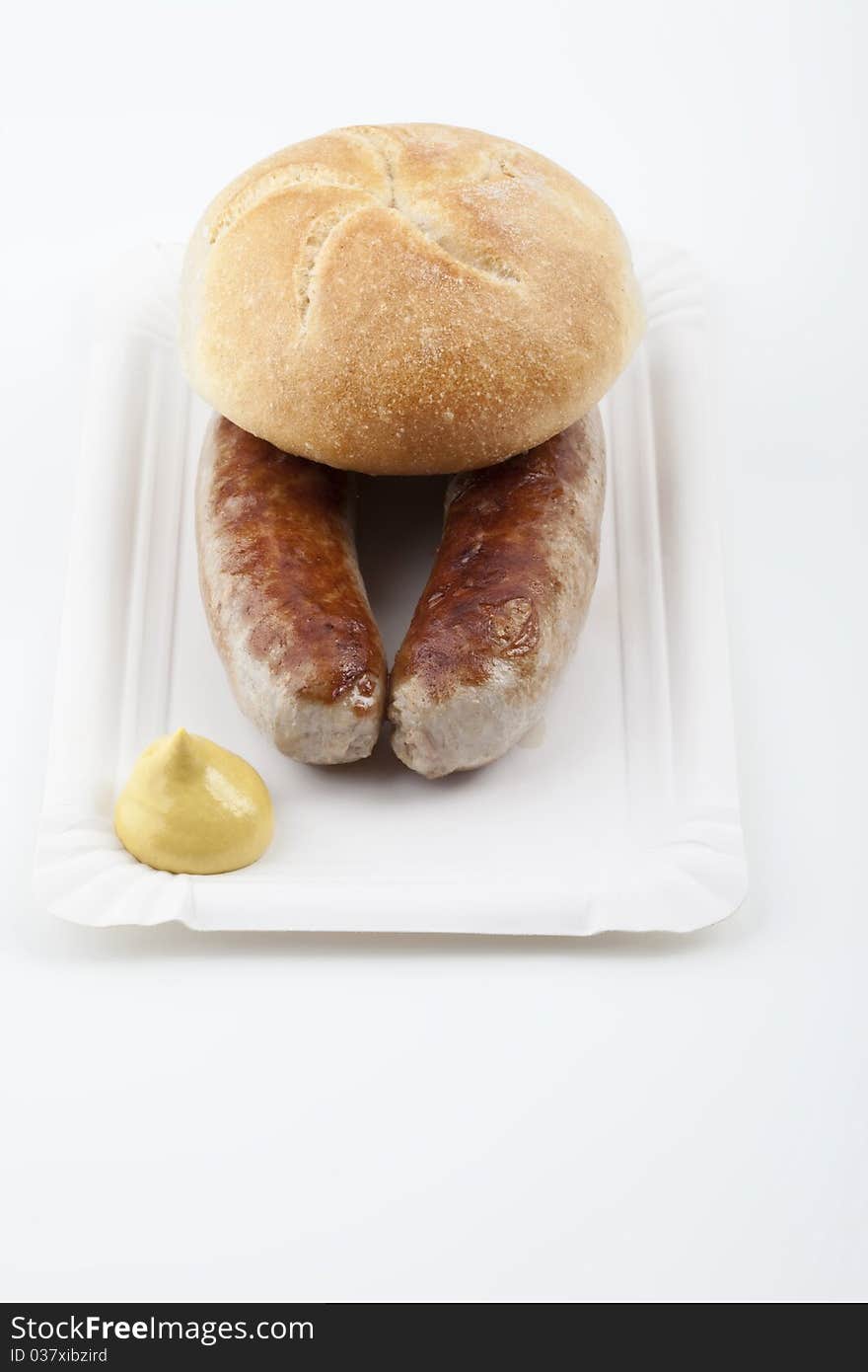 A pair of fried sausages with mustard