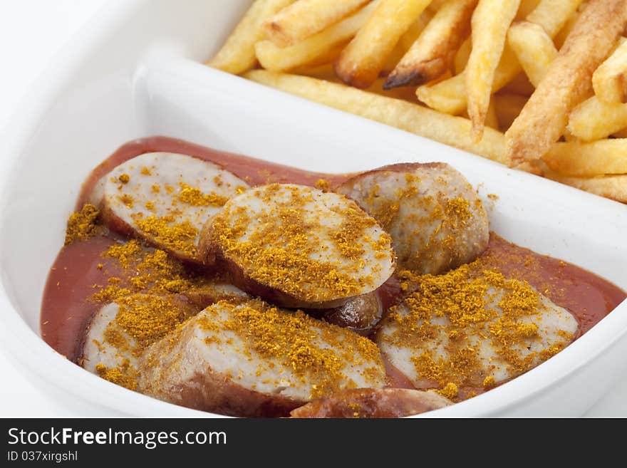 Close-up of curried sausages and french fries on a plate