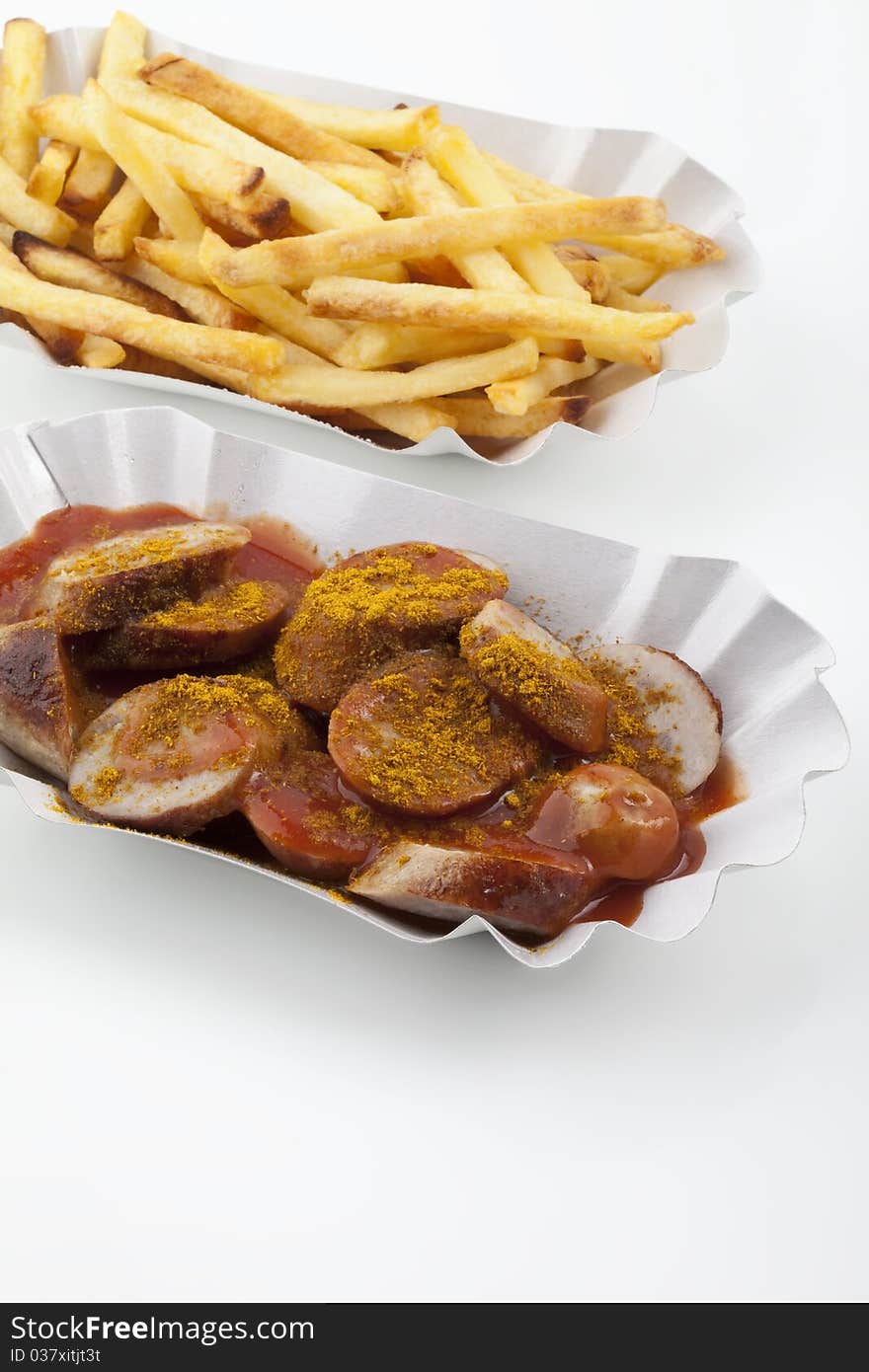 Curried sausages and french fries on paper plates