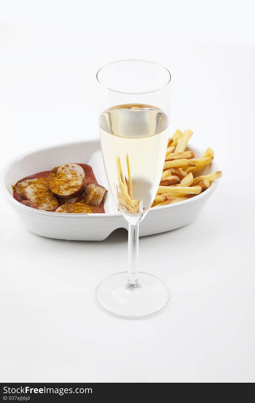 Curried sausages french fries and a glass of prosecco on white background. Curried sausages french fries and a glass of prosecco on white background