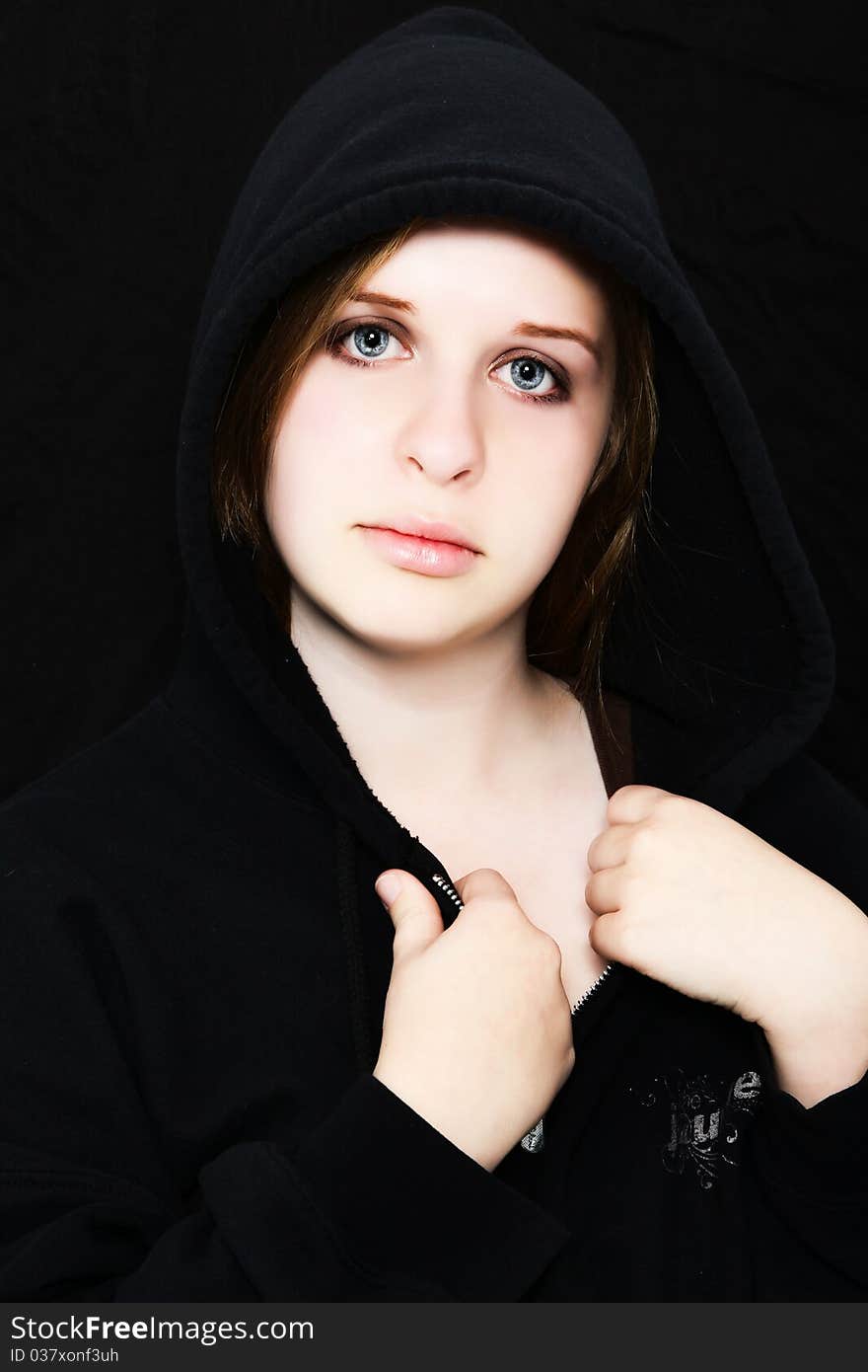 Beautiful 18 year old teenager in black hoodie over black. Pale skin. Serious expression. Beautiful 18 year old teenager in black hoodie over black. Pale skin. Serious expression.