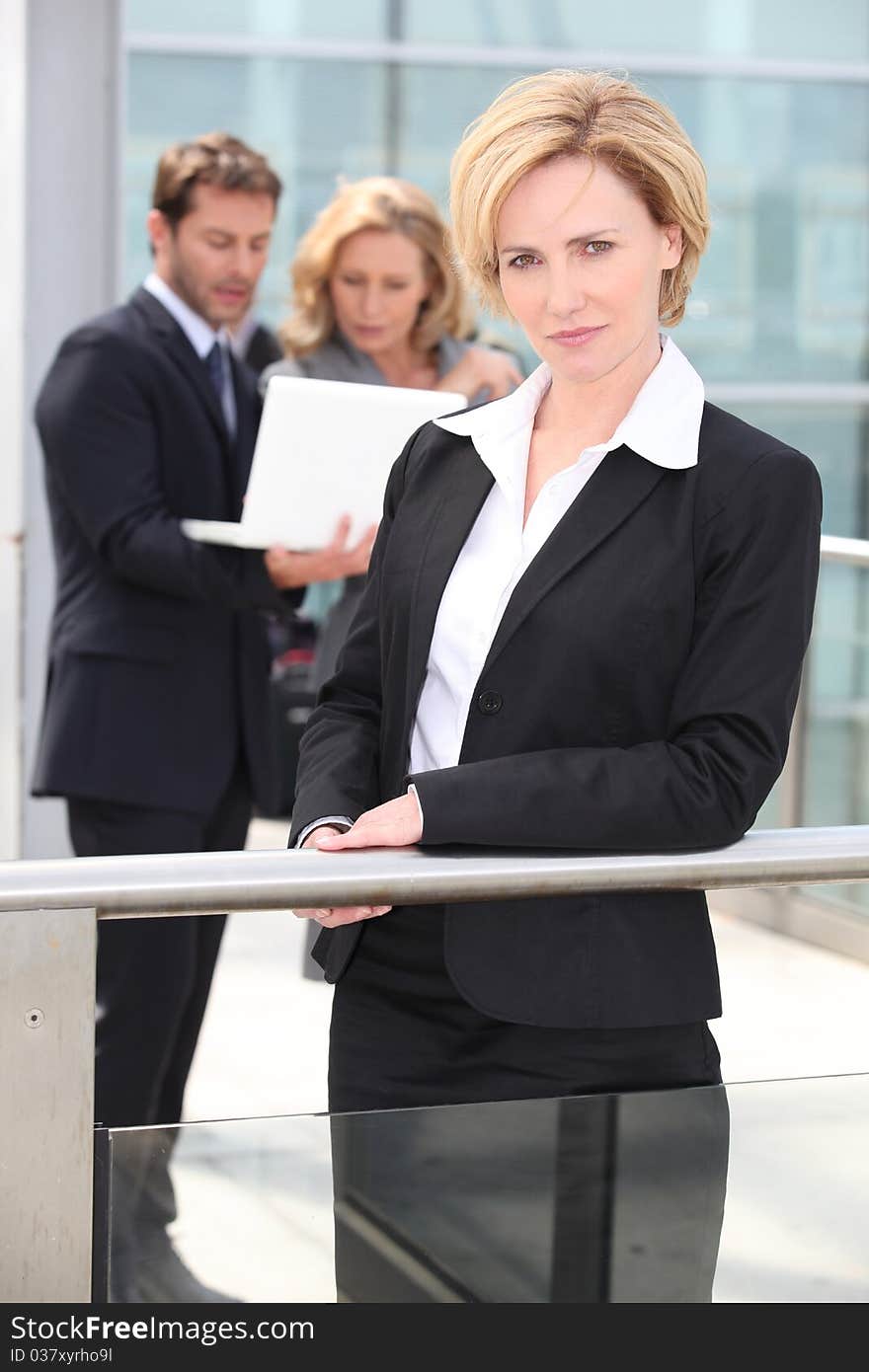 Mature businesswoman standing outdoors in foreground. Mature businesswoman standing outdoors in foreground