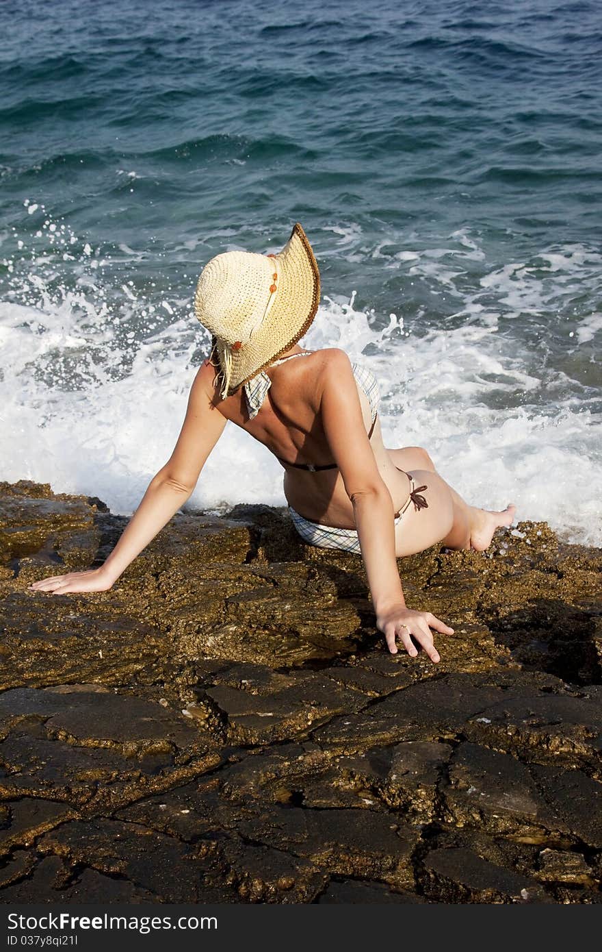 Woman with hat sunbathing on rocks