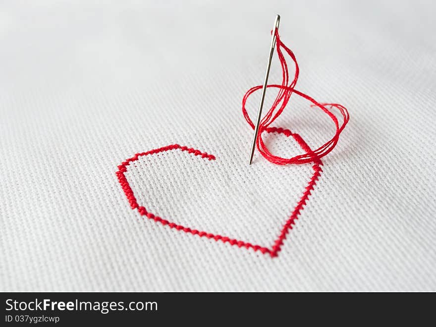 Embroidered red heart on white with needle sticked in canvas. Embroidered red heart on white with needle sticked in canvas