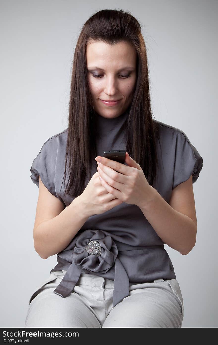 Young caucasian woman in gray dress using a mobile phone. Young caucasian woman in gray dress using a mobile phone