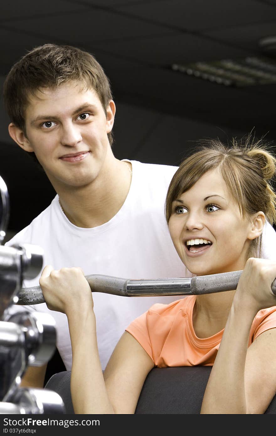 Young beautifull girl and her trainer in fitness club