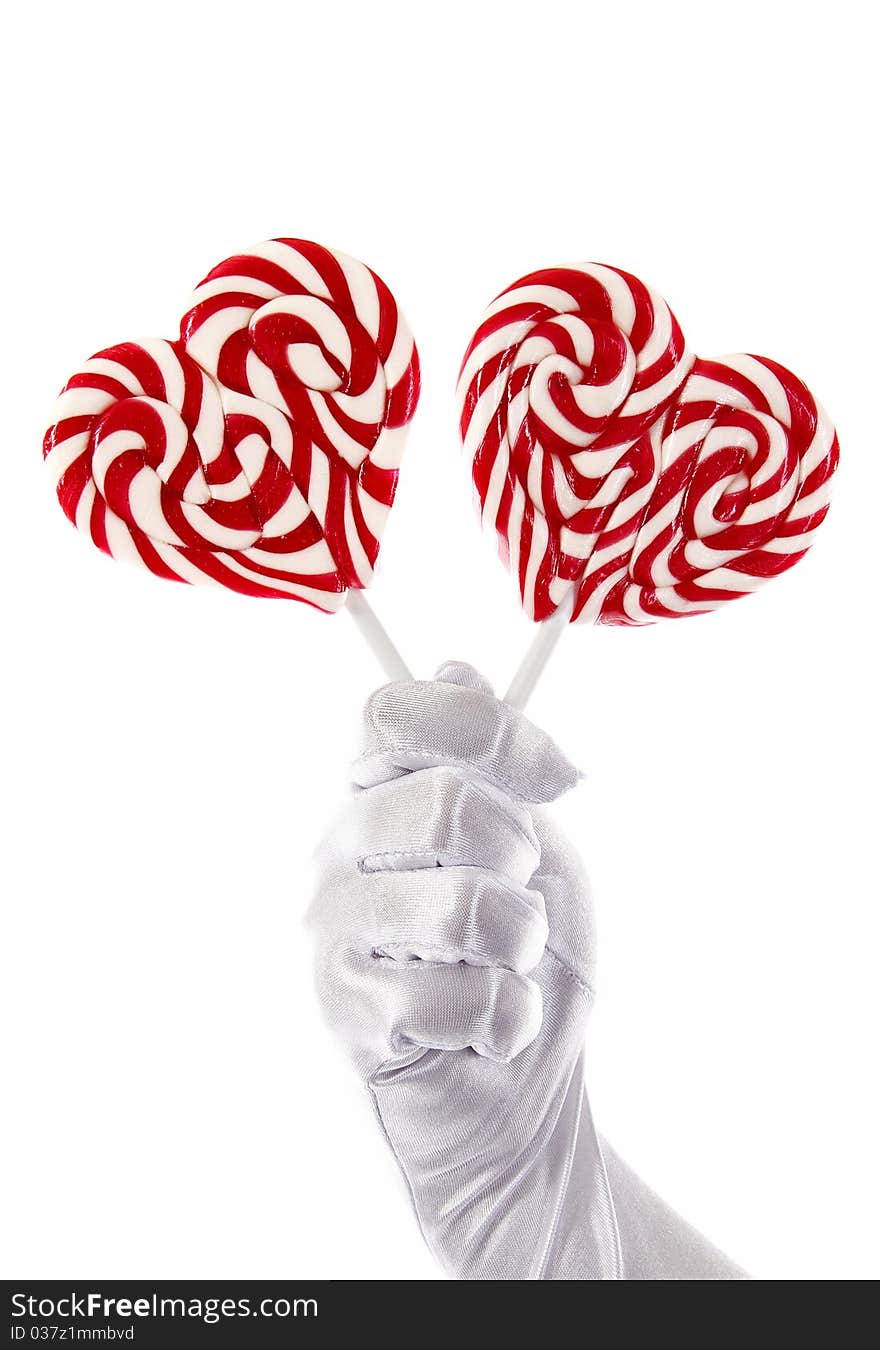 Hand in the white glove holding candies in the shape of a heart. Hand in the white glove holding candies in the shape of a heart