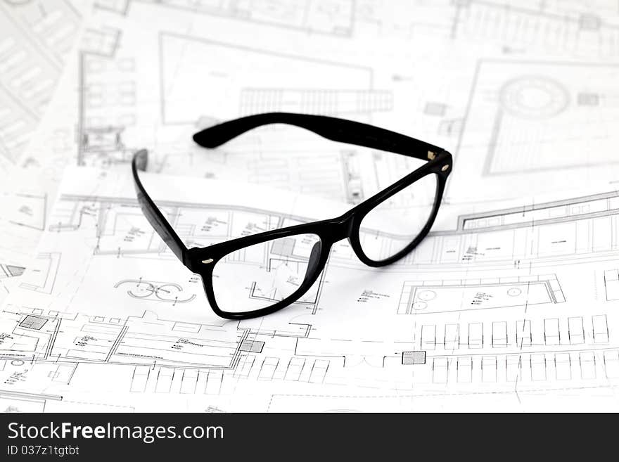 Black glasses on the architectural blueprints in the studio