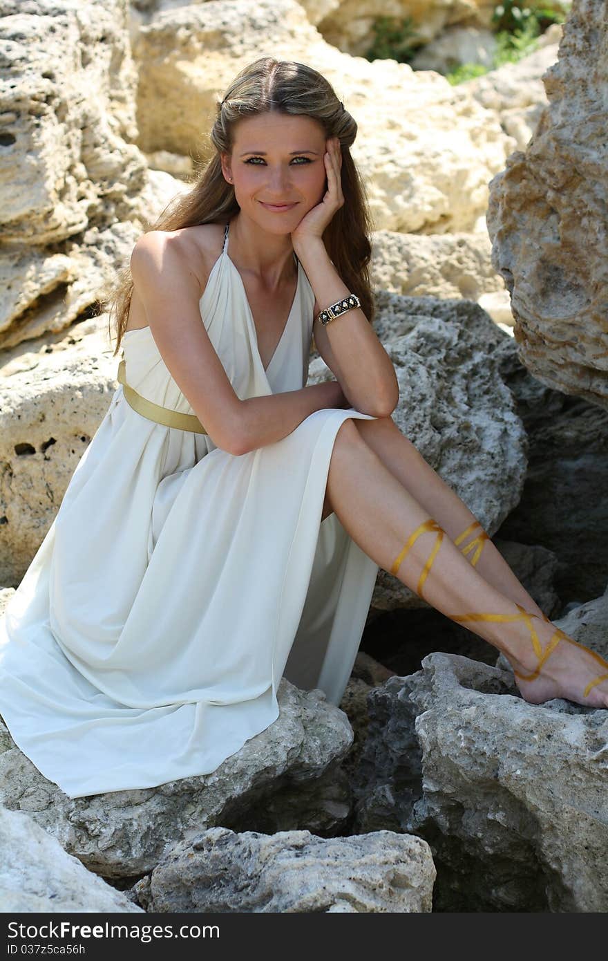 Attractive young woman sitting on the stone