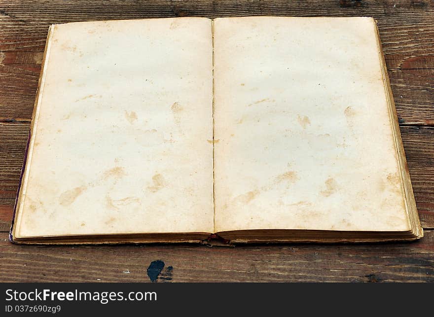 Old book with blank yellow stained pages on wood background