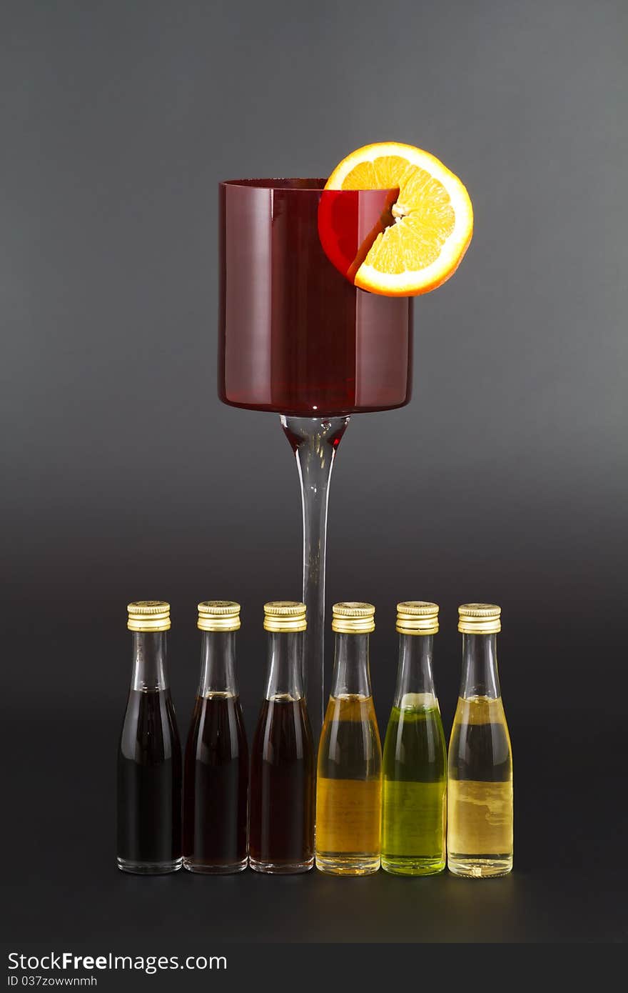 Red Liquor Glass with Orange slice and small liquor bottles