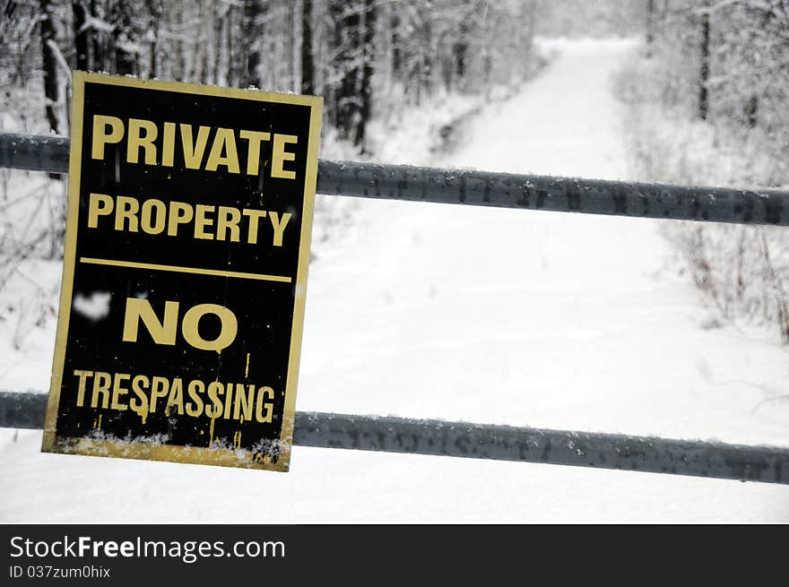 No trespassing sign down peaceful snowy winter lane. No trespassing sign down peaceful snowy winter lane