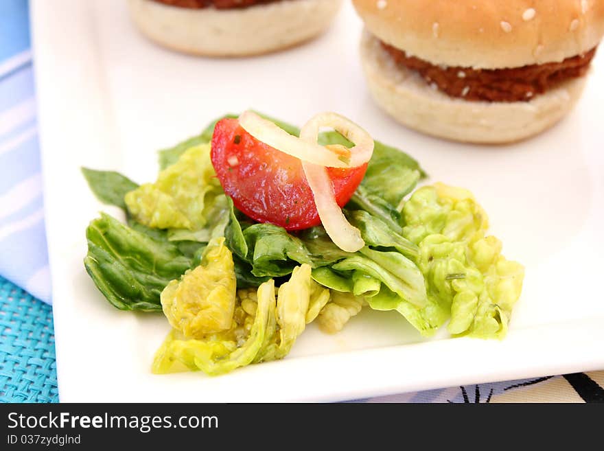 Some small burger with a salad. Some small burger with a salad