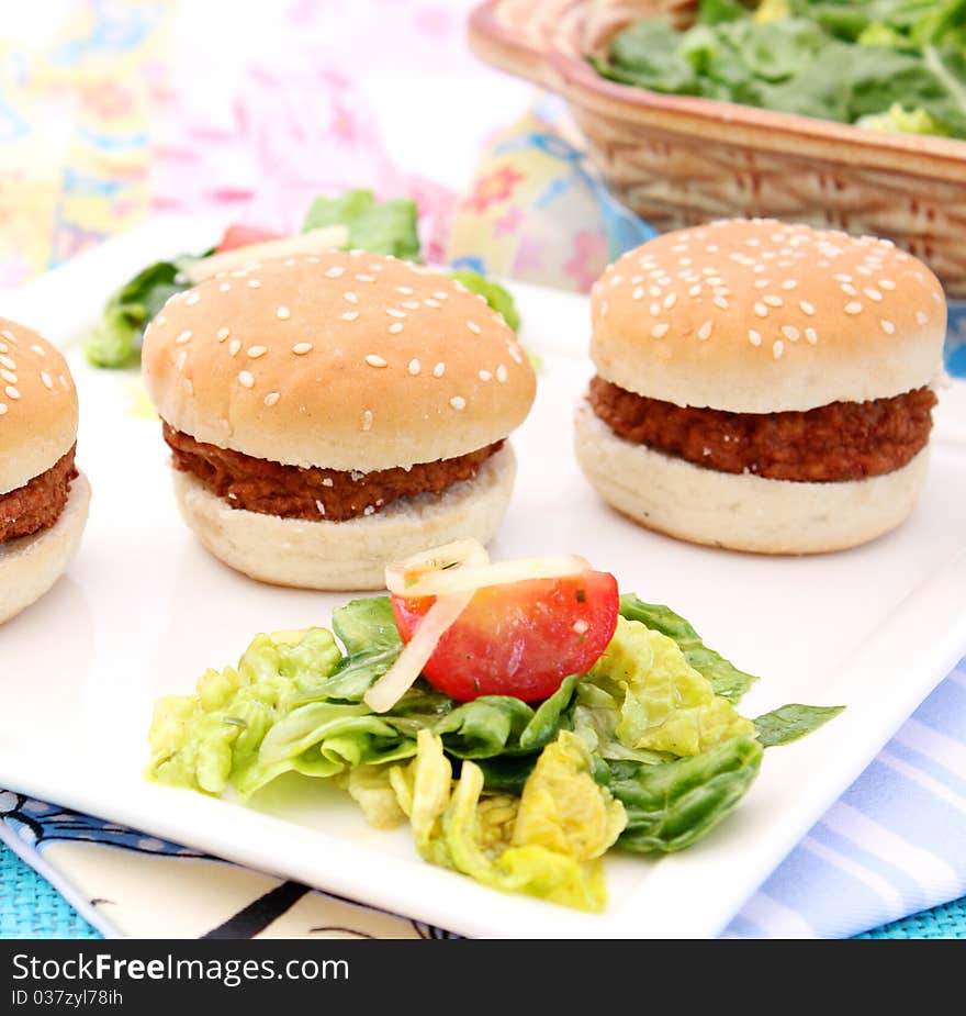 Some small burger with a salad. Some small burger with a salad