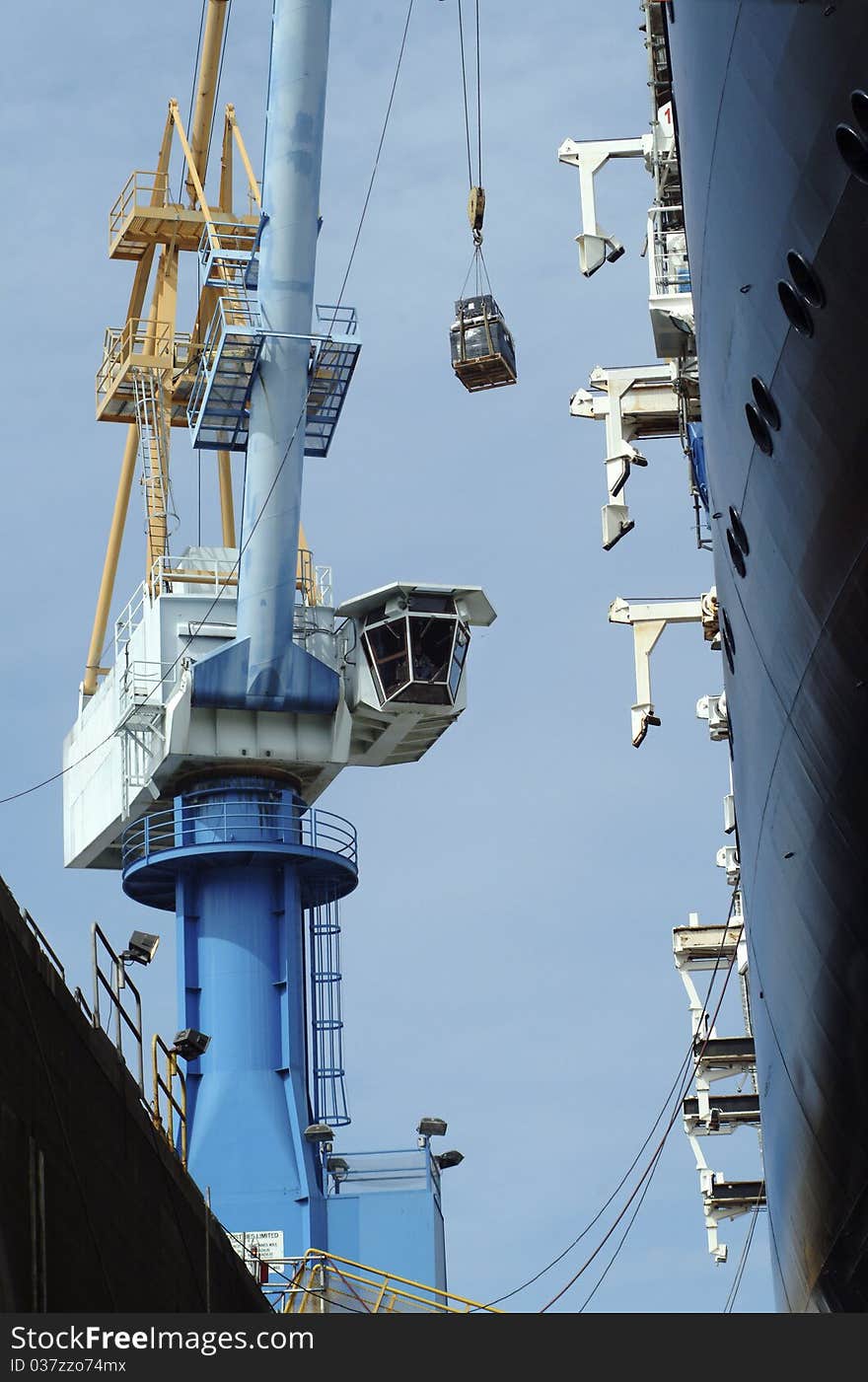 Shipyard crane hoists supplies on to a dry docked ship. Shipyard crane hoists supplies on to a dry docked ship