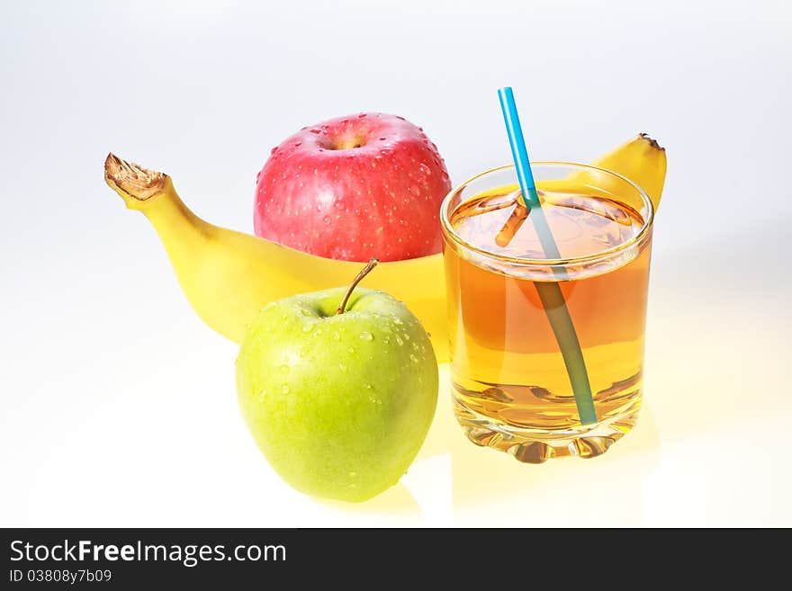 Banana, green and red apples and glass of apple juice with drinking straw. Banana, green and red apples and glass of apple juice with drinking straw