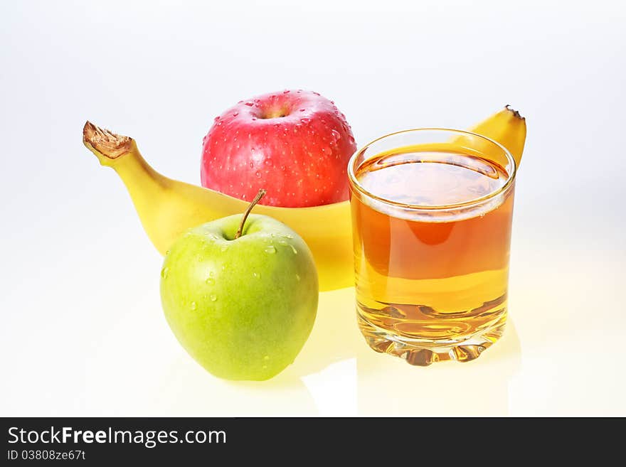 Banana, green and red apples and glass of apple juice