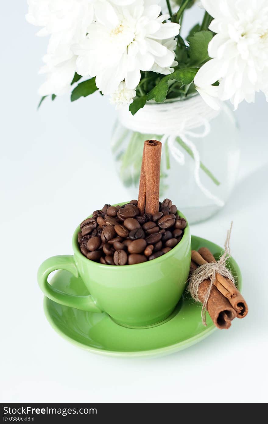 Coffee beans and cinnamon stick in a green cup