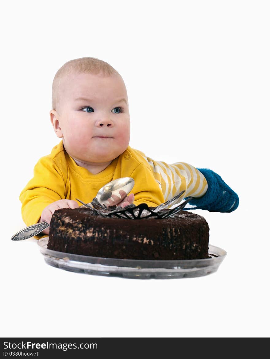 The baby with a big spoon in hand wants to eat chocolate cake