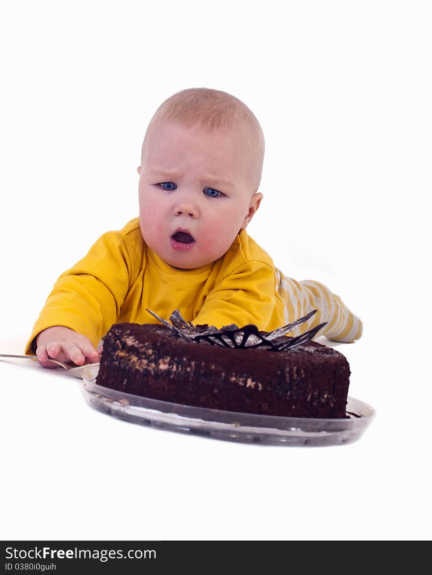 The baby with a big spoon in hand wants to eat chocolate cake