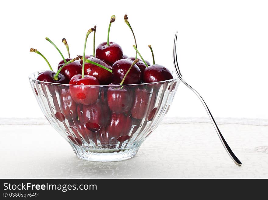 A bowl of fresh cherry with one fruit fork. A bowl of fresh cherry with one fruit fork.