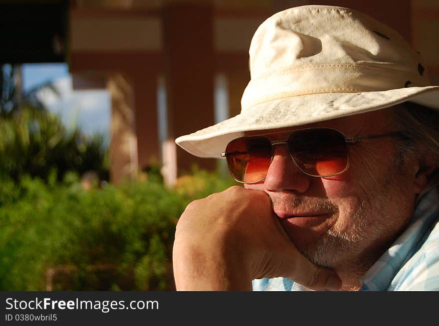 Portrait of a sixty something man with sunglasses and hat in a tourist resort. Portrait of a sixty something man with sunglasses and hat in a tourist resort