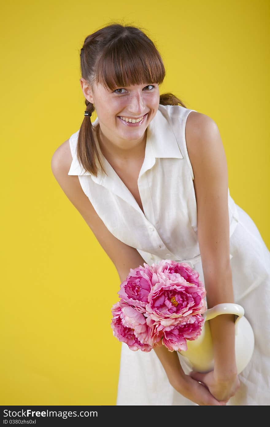 Happy summer woman holding vase with flowers over yellow background. Happy summer woman holding vase with flowers over yellow background