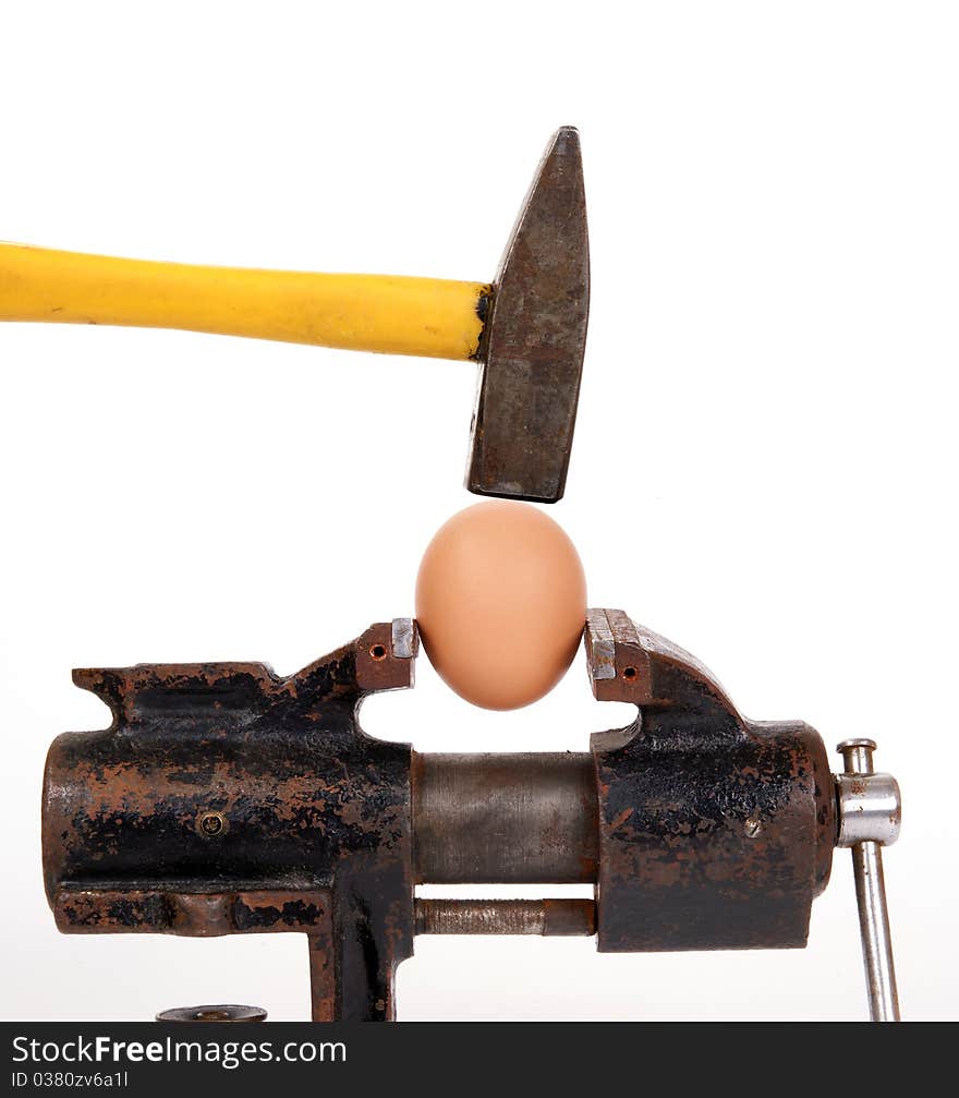 Egg trapped in the old rusty metalwork vice, on a white background