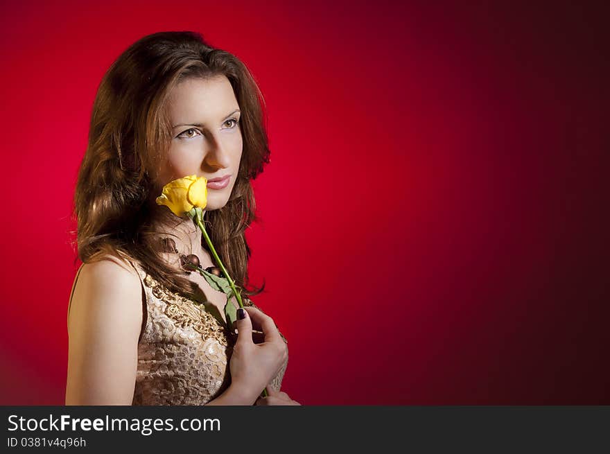 Young girl playing with a yellow rose recived for valentine's day; isolated on a red background