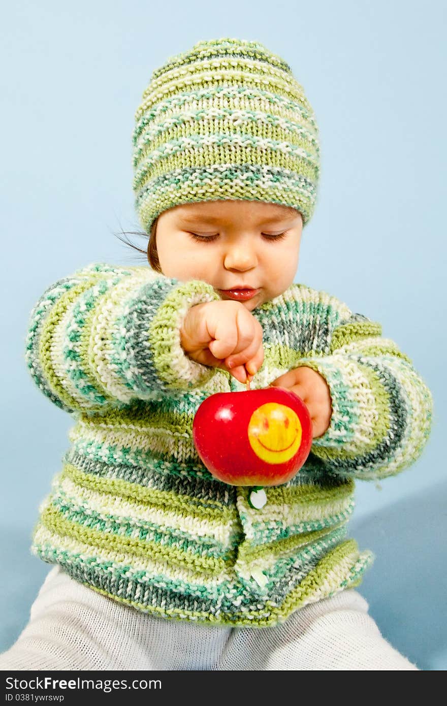 A young Boy is eating a smiling Apple. A young Boy is eating a smiling Apple