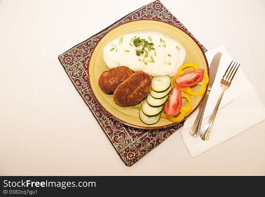 Portion mashed potatoes with meatball and sliced vegetables on a table