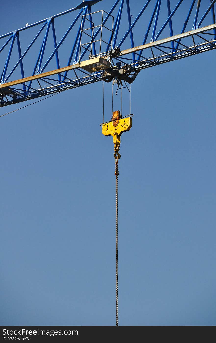 Closeup of yellow jib crane against blue sky. Closeup of yellow jib crane against blue sky