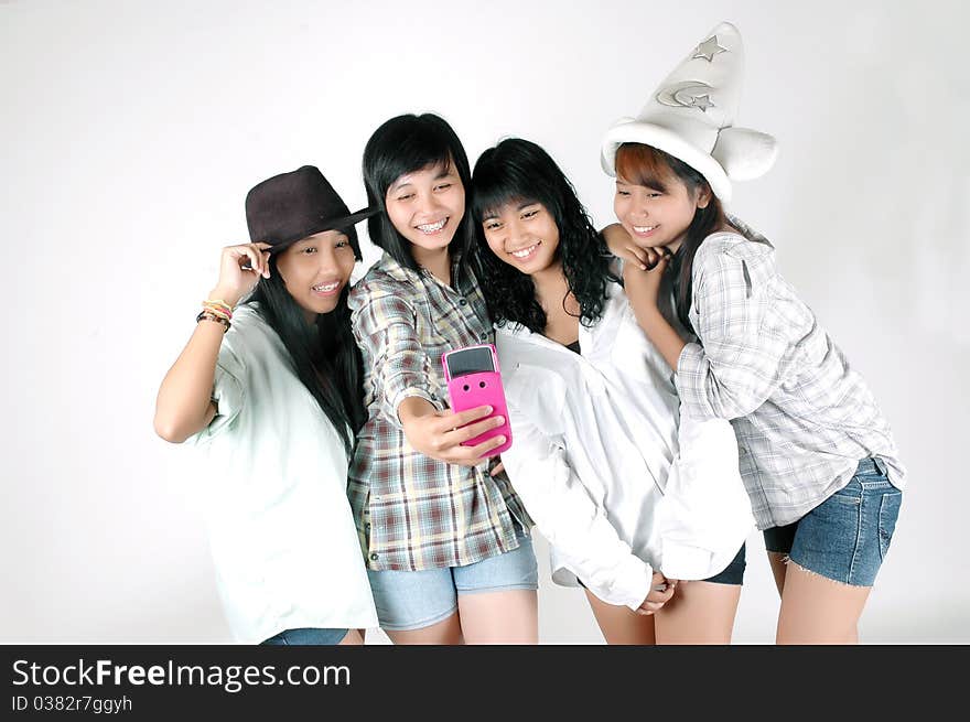 Four teenage girls take pictures using a camera phone. Four teenage girls take pictures using a camera phone