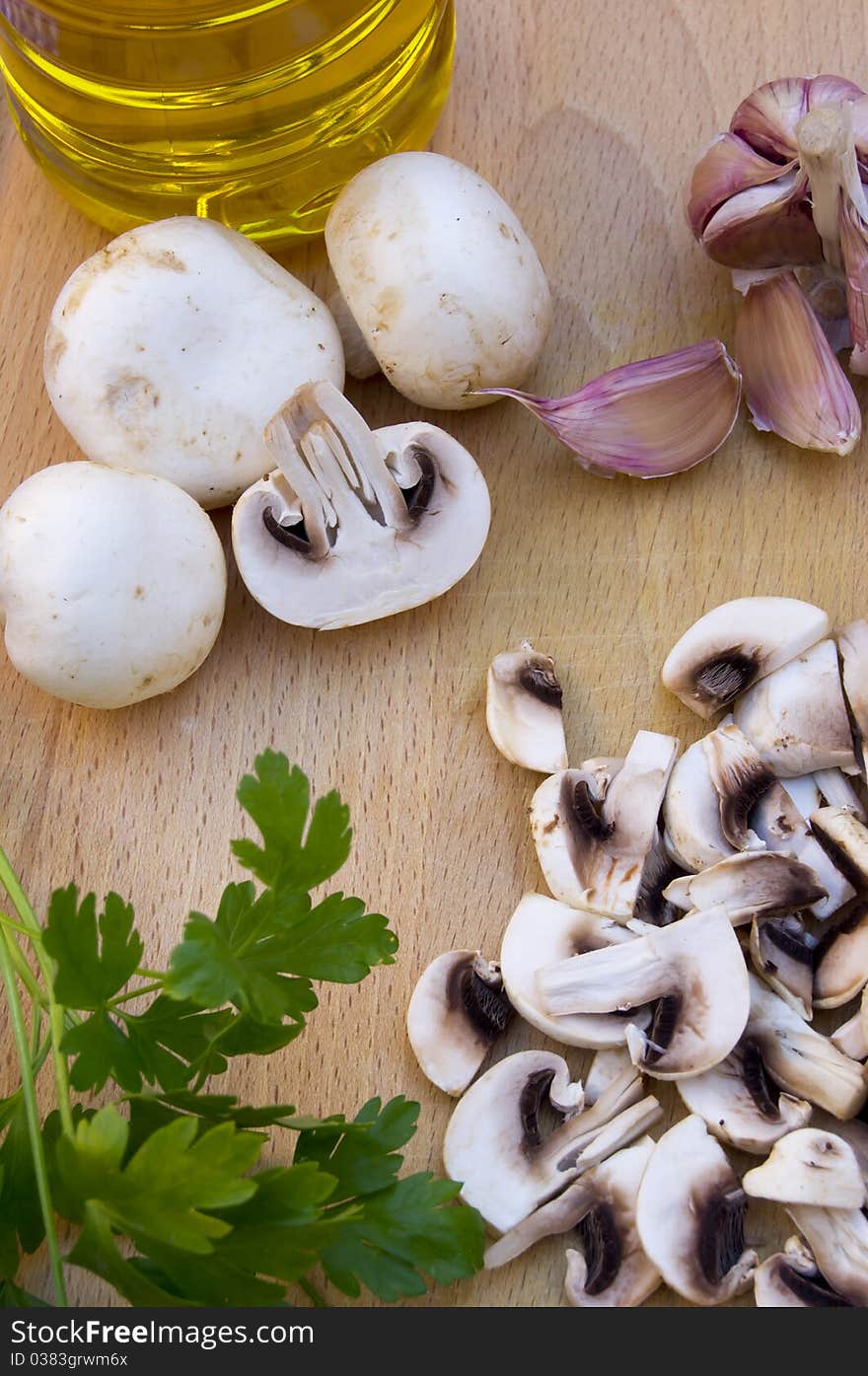 Mushrooms, whole and rolled, with garlic, parsley and olive oil on wood. Mushrooms, whole and rolled, with garlic, parsley and olive oil on wood