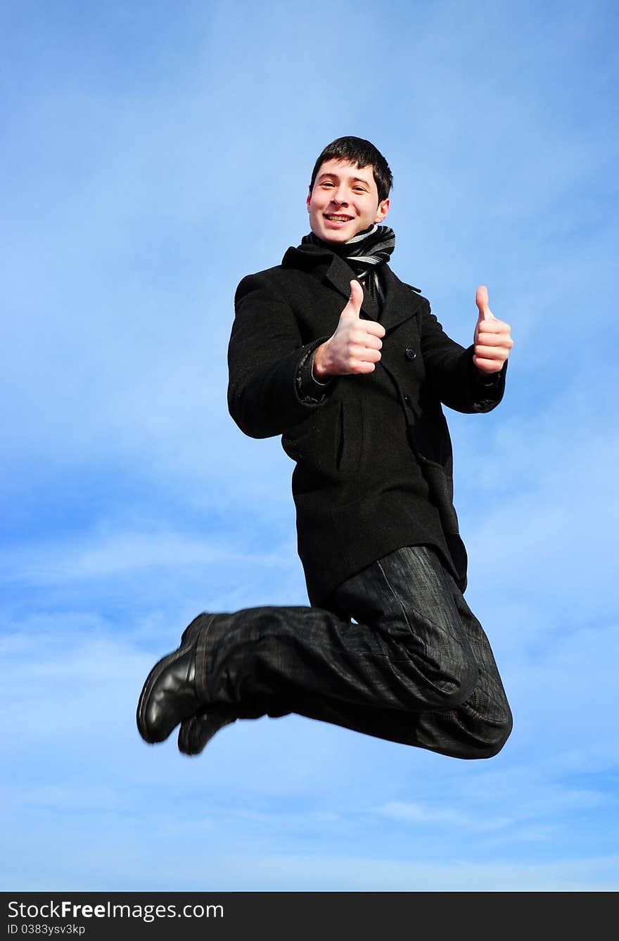 Young man jumping with thumbs up on blue sky. Young man jumping with thumbs up on blue sky