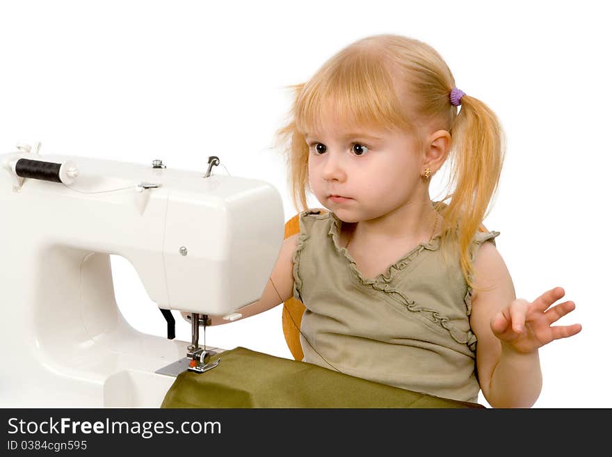 The little girl is sewing on the sewing machine and wonders. The little girl is sewing on the sewing machine and wonders