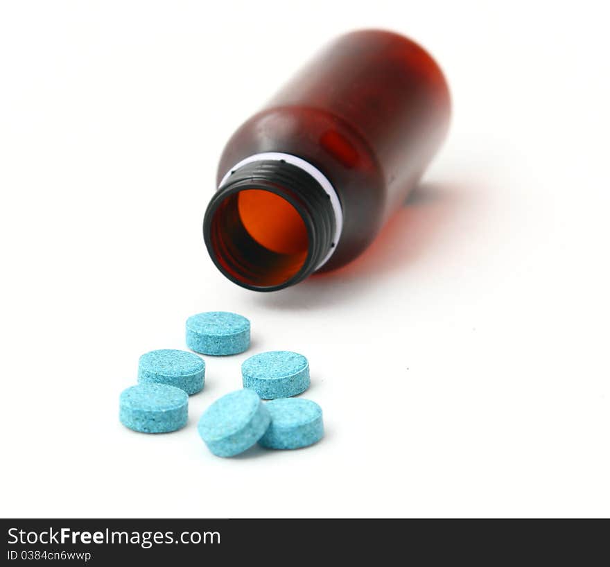 Empty brown medicine bottle and scattered blue pills isolated on white background. Empty brown medicine bottle and scattered blue pills isolated on white background