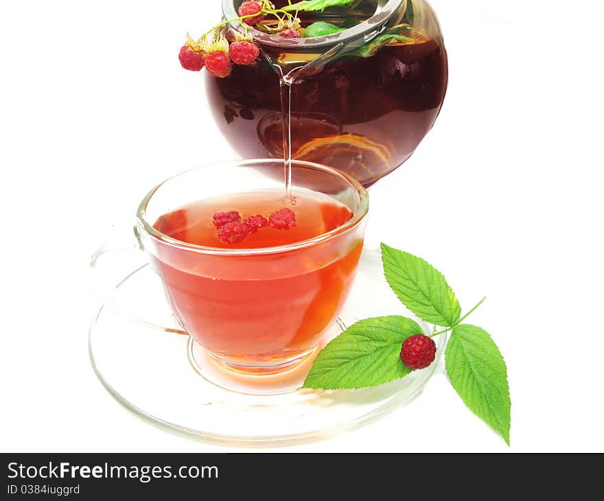 Pouring fruit tea with raspberry berries in teapot and cup. Pouring fruit tea with raspberry berries in teapot and cup