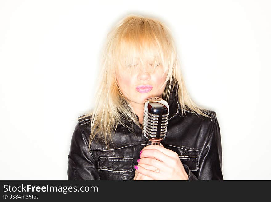 Blonde woman holding a retro microphone wearing black jacket , singing rockstar. Blonde woman holding a retro microphone wearing black jacket , singing rockstar