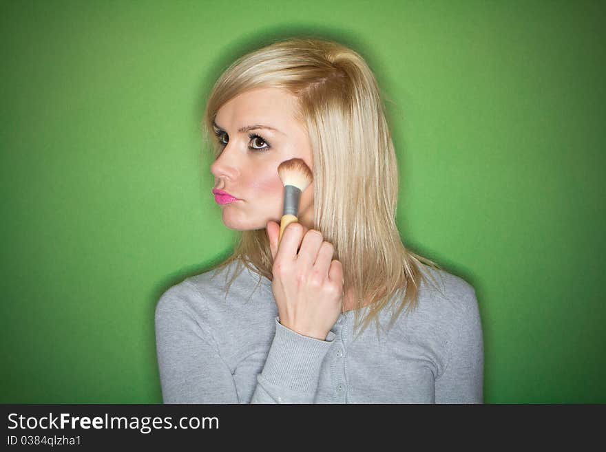 Woman preparing her make-up and hair before the party , on green background. Woman preparing her make-up and hair before the party , on green background