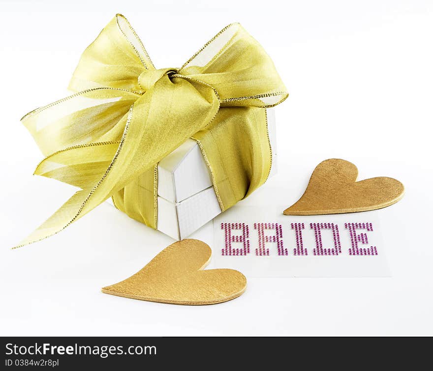 White jewelry box with gold ribbon, 2 gold hearts, and bride shown in pink lettering on white background. White jewelry box with gold ribbon, 2 gold hearts, and bride shown in pink lettering on white background