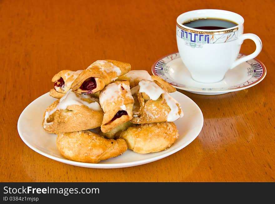 Plate of fresh golden brown assorted pastry with a cup of aromatic coffee on old wooden table. Plate of fresh golden brown assorted pastry with a cup of aromatic coffee on old wooden table