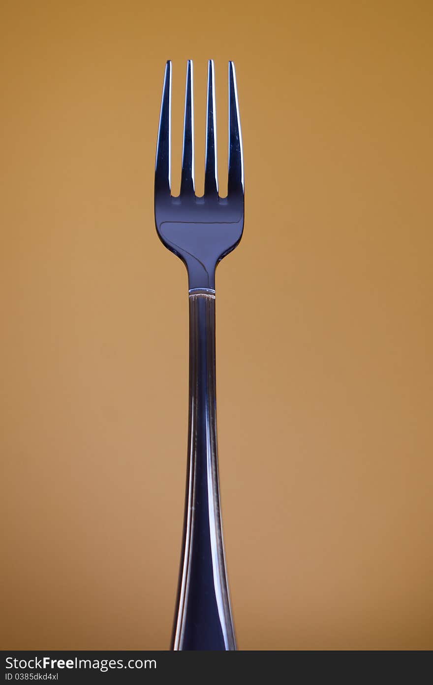 Traditional stainless dishware - fork on clolour background. Selective focus.