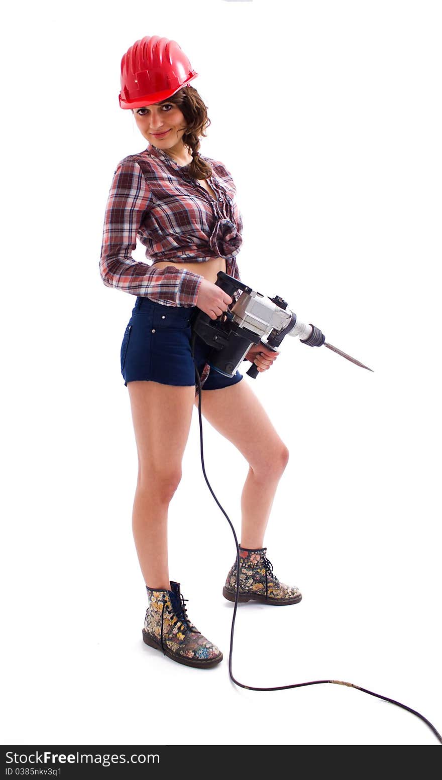 Beautiful young girl with a red helmet standing with drill in her hands. Beautiful young girl with a red helmet standing with drill in her hands