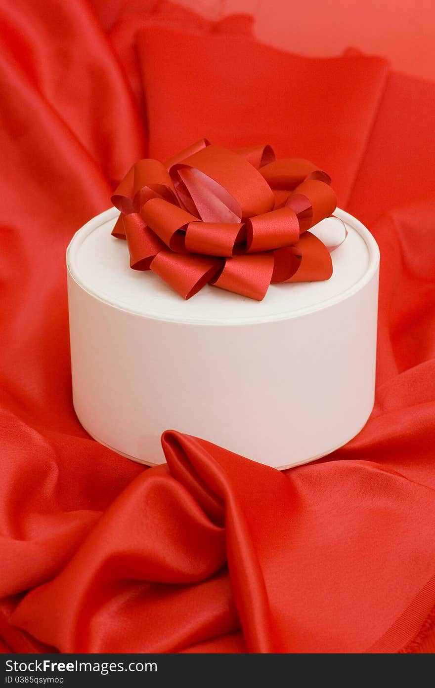 Box with a gift on a red fabric still life