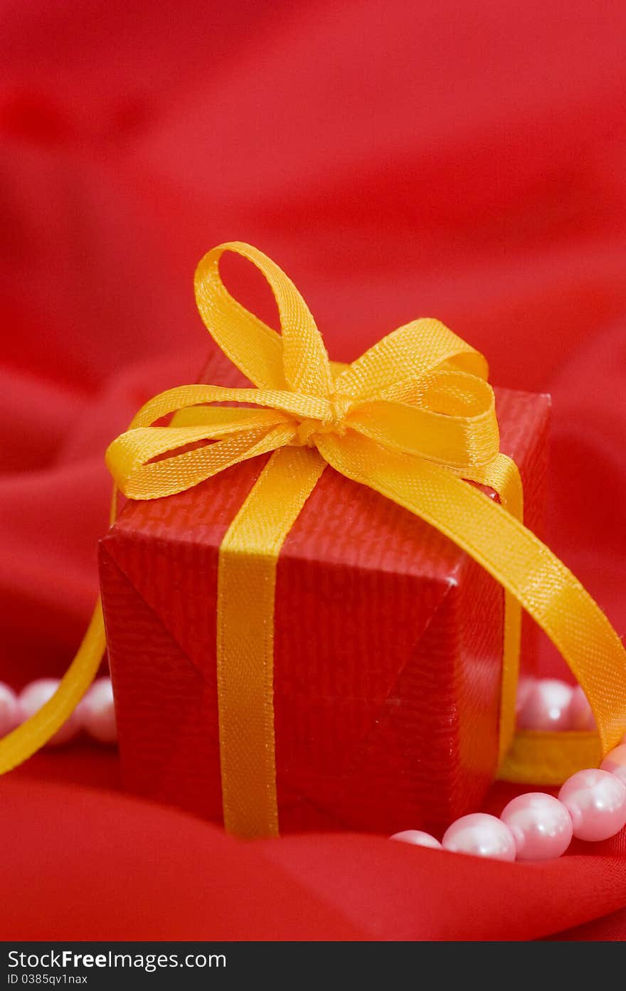 Box with a gift on a red fabric close up