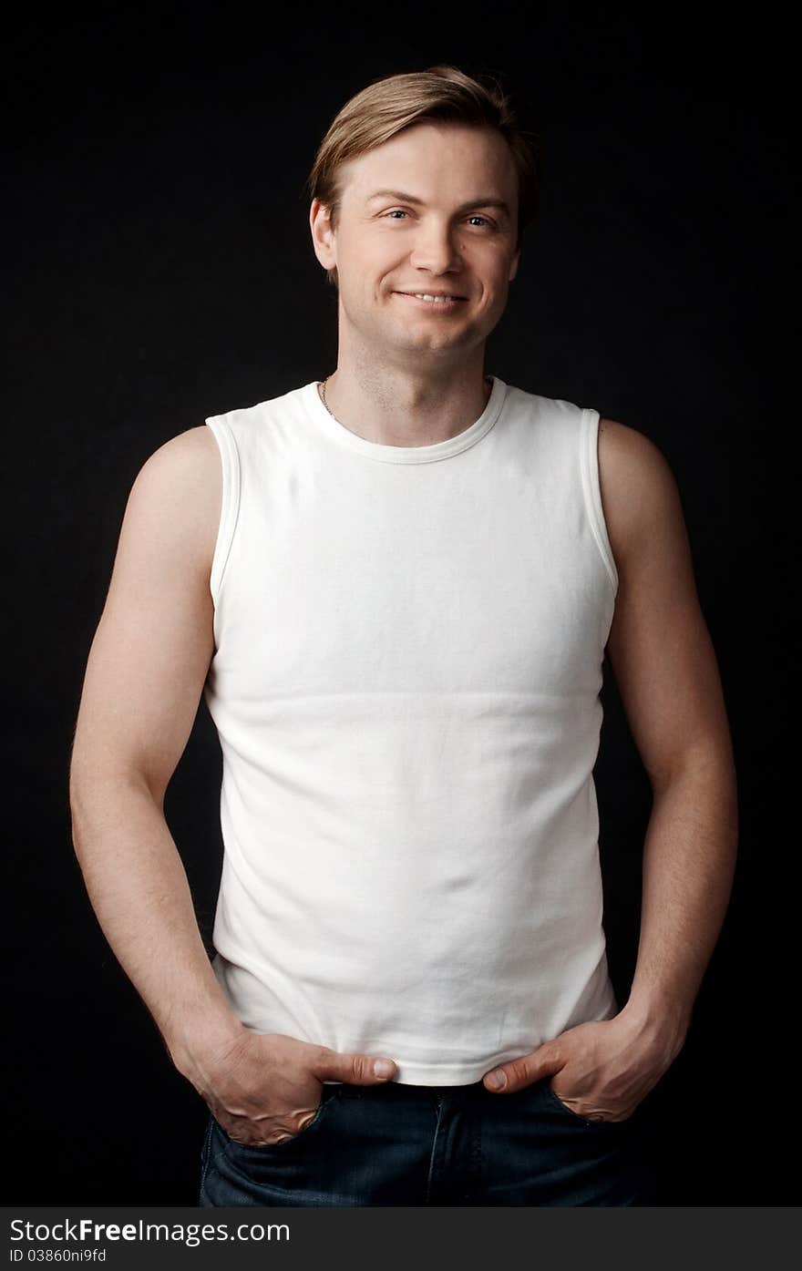 Smiling young guy in the white shirt on the black background